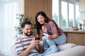 Happy couple shopping online using credit card and smartphone at home