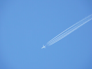 White streaks of planes leave behind like clouds crossing the image diagonally across the photograph on a blue sky background