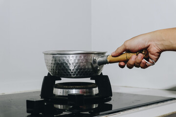 A Skillful Hand Holding a Steel Pan Over a Modern Stove Preparing a Delicious Meal