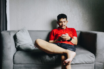 A Young Man Relaxing on a Cozy Sofa While Engrossed in His Mobile Device in a Modern Space