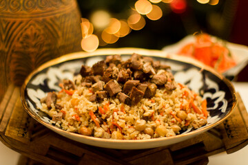 Traditional Uzbek pilaf served in a decorative bowl, featuring tender meat, rice, and vibrant vegetables, showcasing the rich culinary heritage of Uzbekistan. Copy space, menu