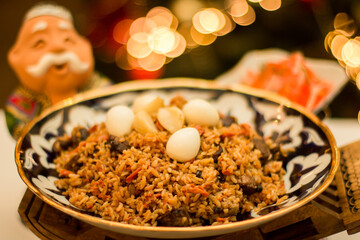 Traditional pilaf Uzbek rice dish served in a decorative bowl, featuring tender meat, spices, and quail eggs, embodying the essence of Uzbek cuisine. Copy space, menu