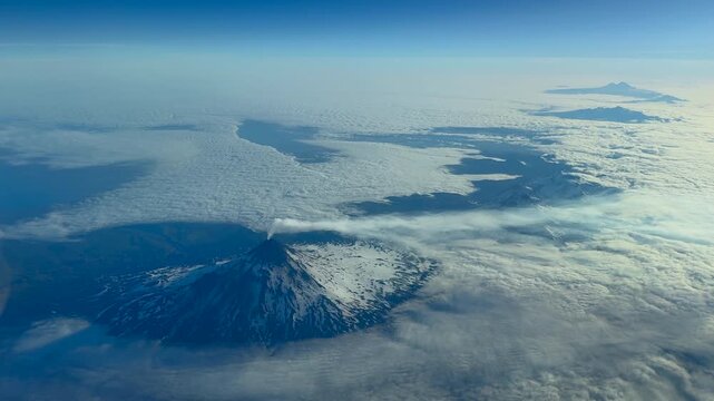 An aerial view of a  volcano south of King Salmon Alaska emits smoke from its summit.