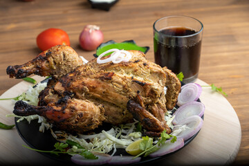 Crispy delicious whole chicken tandoori with vegetables or salad served in plate 