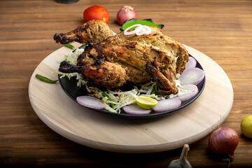 Crispy delicious whole chicken tandoori with vegetables or salad served in plate 