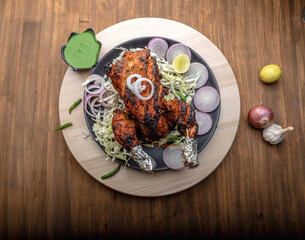Crispy delicious whole chicken tandoori with vegetables or salad served in plate 