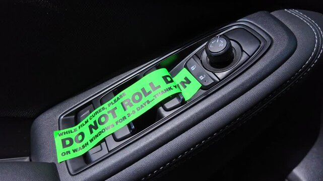 Green sticker on the car door says, While film cures do not roll down or wash windows for 3 to 5 days after installation of tinting film on the car glass. Protective UV film and tint on the car glass.