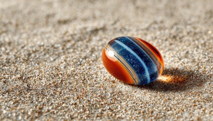 Obraz premium A colorful glass marble rests on sandy terrain