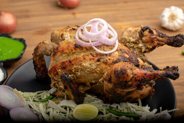 Crispy delicious whole Afghan  chicken tandoori with vegetables or salad served in plate 