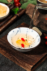 Traditional Asian sweet dessert with colorful jellies and yellow grain in ceramic bowl with syrup pouring