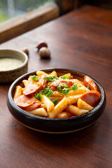Korean street food, tteokbokki with sausages and sesame on the table vertical photo