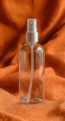 Fototapeta premium Clear spray bottle on orange fabric (1)