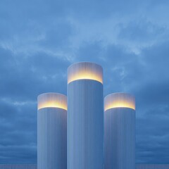 Three tall, light-blue cylindrical structures stand against a cloudy twilight sky.  Soft, warm light emanates from within their tops
