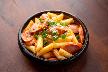 Korean street food, tteokbokki with sausages and sesame on the table