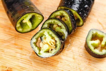 Fresh Black Purple Bell Pepper Slices with Green Interior on Wood Cutting Board