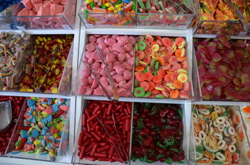 Various colorful candies stored in transparent plastic containers. Bright and cheerful sweets in different shapes and colors, symbol of childhood, sugar, and indulgence.
