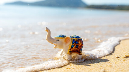 Obraz premium Souvenir elephant figurine on the beach by the sea. Tourism Travel Concept