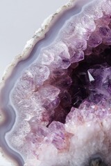 Obraz premium Close-up of a polished amethyst geode slice. A smooth, pale-lavender agate outer ring surrounds a cluster of deep-purple amethyst crystals