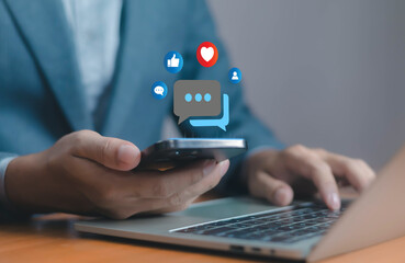 Businessman using smartphone and laptop with social media icons, representing online communication, digital marketing, customer engagement, networking, social interaction, modern business technology.