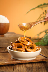 Honey Drizzled Fried Squid Rings in Bowl on Wooden Table with Spoon and Tropical Background