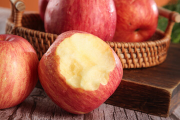 Fresh Red Fuji Apples in Wicker Basket on Wooden Table with Bite Taken