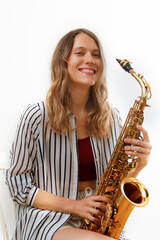 Fototapeta premium Smiling saxophonist playing her saxophone on white background