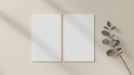 Two white invitation cards mockup with an eucalyptus decoration on the beige table. 5x7 ratio, similar to A6, A5