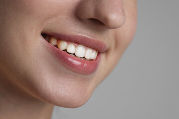 Obraz premium Smiling woman after dental aligners treatment on grey background, closeup. Space for text