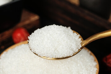 White granulated sugar on golden spoon close-up macro shot showing fine crystal texture