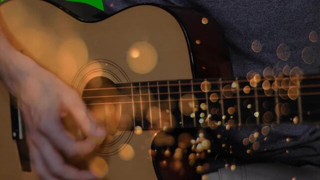 On start, musician plucking, strumming guitar strings as bokeh lights drifting for practice rhythm