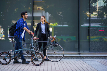 Obraz premium Asian man and woman walking with bicycles in the city on their way to work.