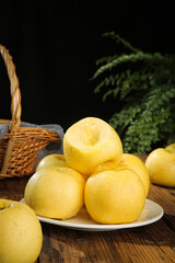 Fresh Golden Yellow Apples on Rustic Wooden Table with Wicker Basket and Fern Background