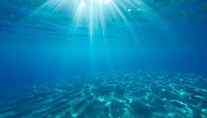 Naklejka premium Sunlight filtering through clear blue ocean water onto sandy seabed, creating mesmerizing light patterns and a tranquil underwater scene
