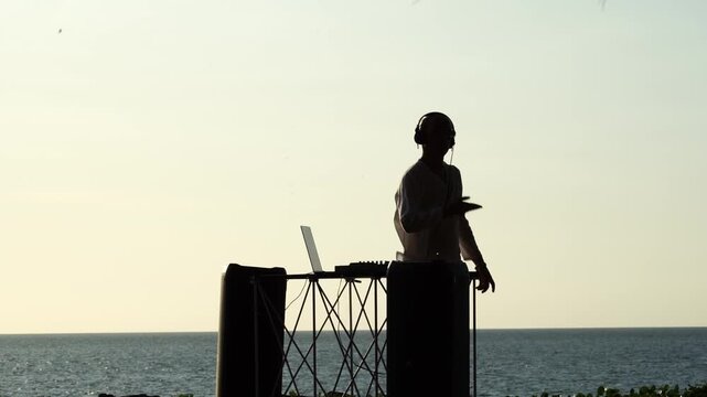 DJ playing music at sunset by the sea
