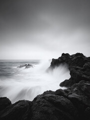 Obraz premium Dramatic monochrome seascape. Powerful waves crash against dark, rugged rocks. Long exposure creates a misty, ethereal effect. Ideal for nature, strength, and resilience themes.