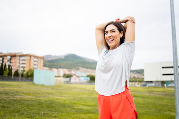 A woman between 40 and 50 years old is training outdoors in sportswear.The woman stretches her arms...