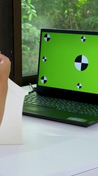 Child looks at laptop webcam making video call. Learning math at elementary school from home. Distance education concept with e-learning. Online class using webcam. Green screen on laptop