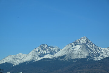 A distant view from the hill of the high peaks of snow-capped mountains High Tatra in spring
