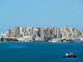 Fototapeta premium Alexandria, Egypt - 05.04.2025 Alexandria shipyard with blue cranes, naval-industrial facilities, and residential high-rise buildings in the background along the Mediterranean coast.