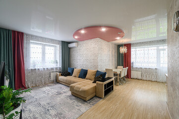 Cozy living room with a sectional sofa, dining area, soft rug, and colorful curtains. Bright, modern interior design