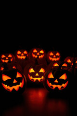 Cluster of Halloween pumpkins glowing in the dark with a black background