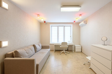 bright, minimalist room with a neutral palette. Features a sofa, desk, chest of drawers, window, and varied lighting