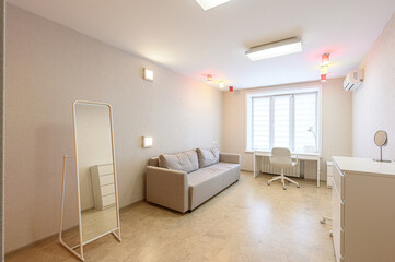 Bright interior. Sofa, desk, mirror, and cabinets in a beige and white palette. Modern design