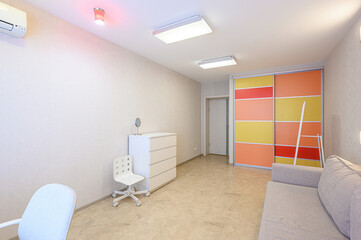 Fototapeta premium Bright, clean room with a gray sofa, white dresser, chair, and colorful sliding door wardrobe