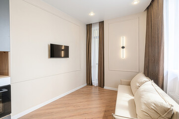 right, modern room featuring a TV on the wall, sofa, window with curtains, and wooden floor. Minimalist design with neutral tones