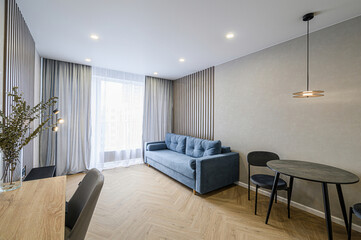 Cozy living space with a blue sofa, wooden accents, and a modern table setting. Light and airy ambiance