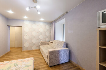cozy living room interior with a patterned sofa, wood floors, light walls, and a unique circle-patterned wallpaper accent wall