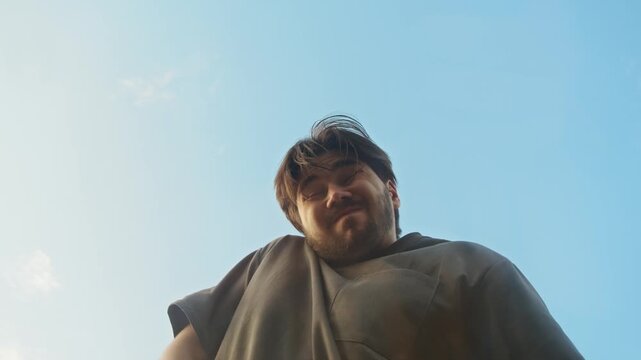 A man on the street looks around and unbuttons his pants, then starts to urinate in the wrong place. Low angle. Slow motion.