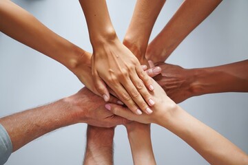 A group of diverse hands stacked together in a show of unity and teamwork on light background