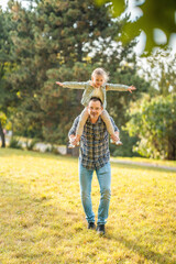 Young father and funny little daughter having fun together in autumn park in Prague, Europe